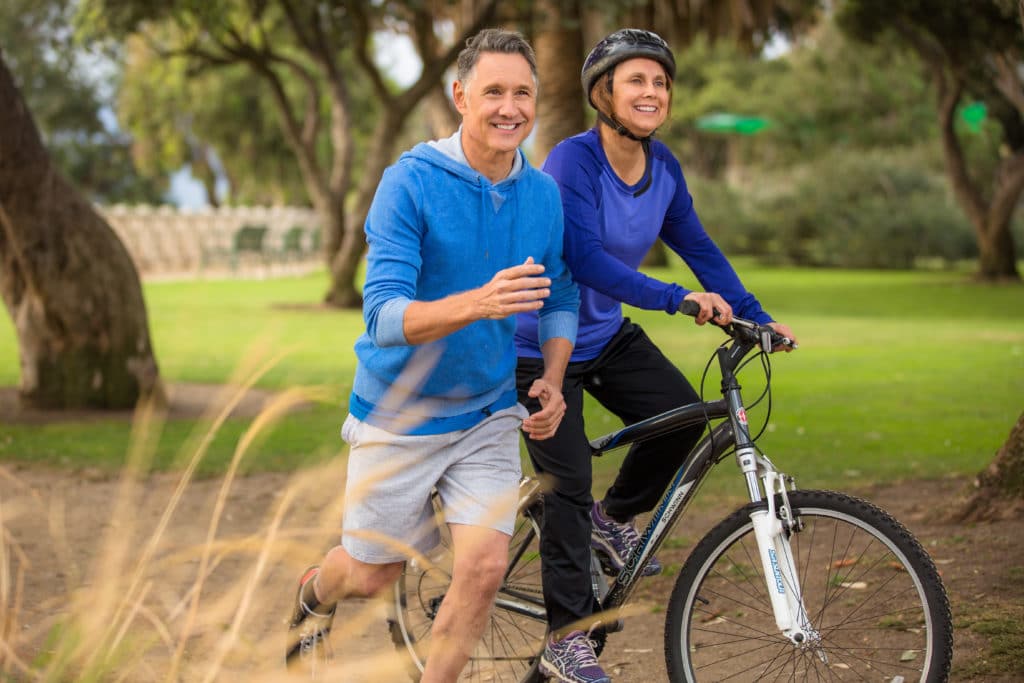 Two older individuals going on a morning jog and bike ride after total hip replacement surgery