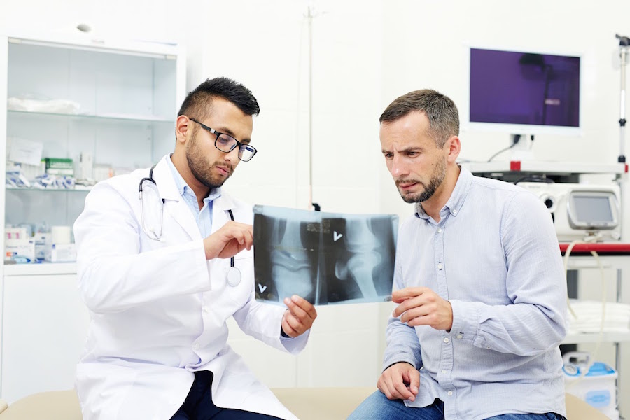 A doctor reviews X-ray images with a patient.